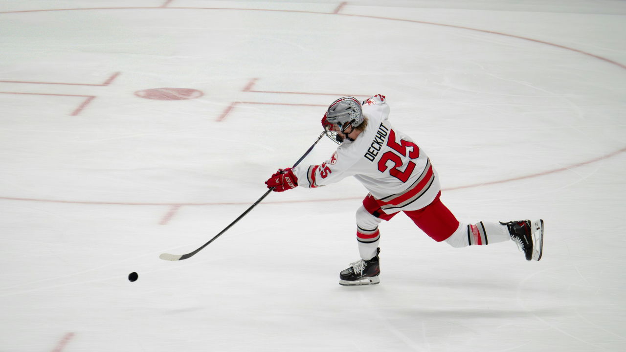 A player in a white and red jersey ripping a shot across open ice